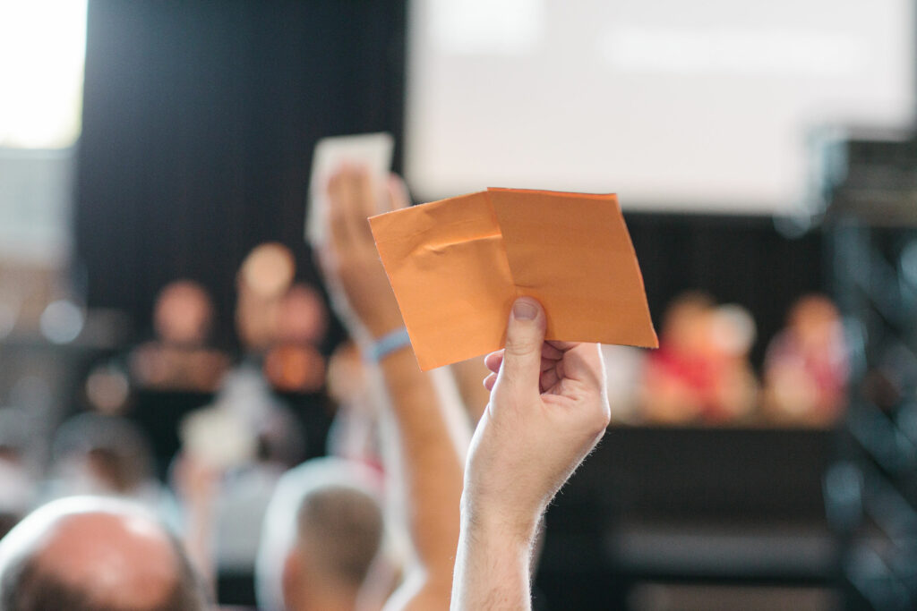 An FSE memer holds up an orange voting card at the 2022 BGM. 