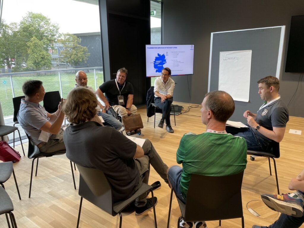 Participants in a workshop sit in a circle and discuss EURO 2024. 